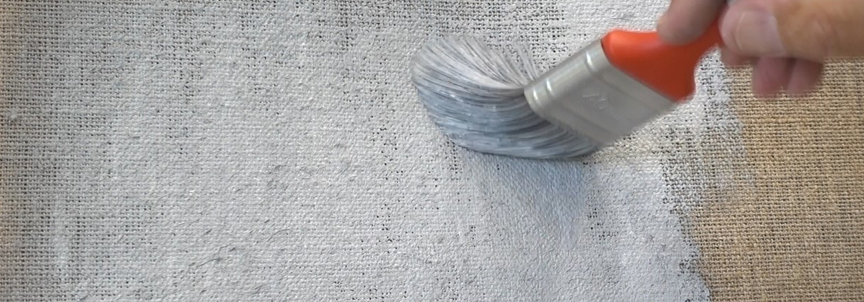 Ein Pinsel bemalt eine Leinwand mit grauer Farbe